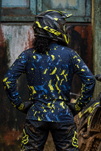 Load image into Gallery viewer, Neon Grunge Men's Riding Jersey back view featuring bold neon yellow and blue paint-splatter graphics on a dark navy base, worn by an off-road rider.